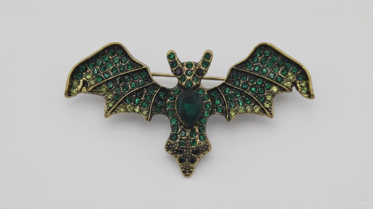 “Short video showing a bat-shaped brooch with outstretched wings and green jewel detailing.”
