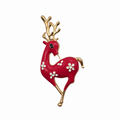 A festive Christmas reindeer brooch featuring a glossy red body, gold-plated antlers and legs, and small white enamel flowers on its side, set against a plain white background.