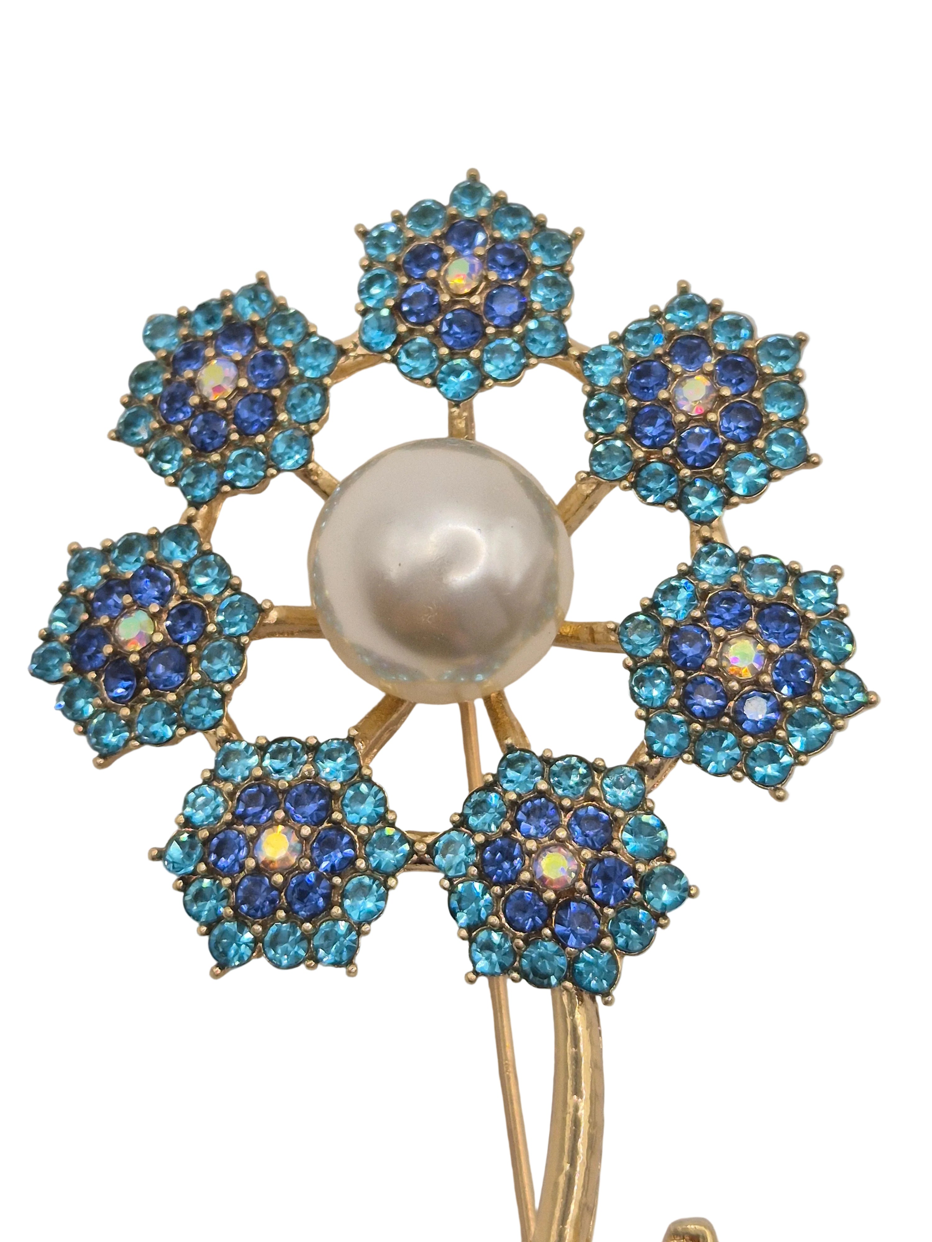 Floral brooch with blue gemstones and a pearl center on a white background