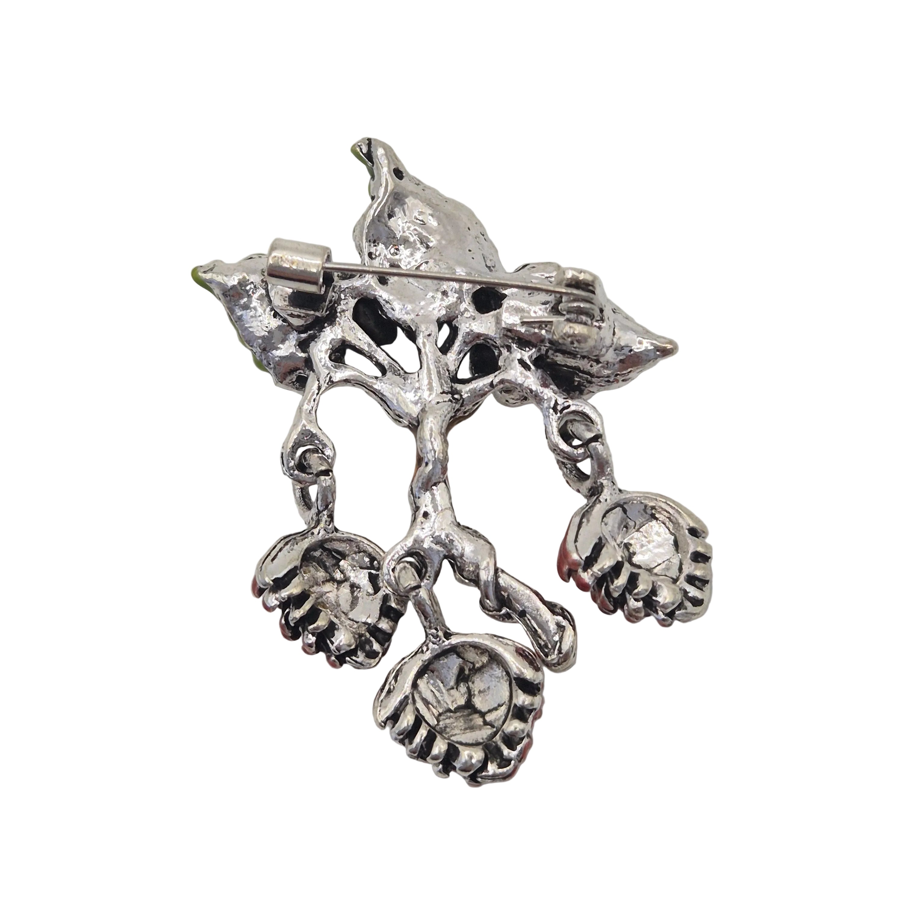 Reverse silver side of brooch of a branch and three dangling pinecones on a plain white background.