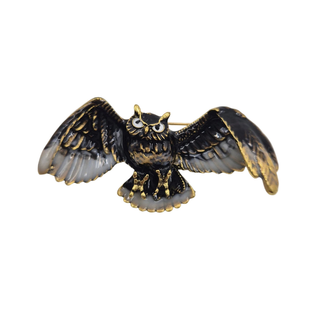 An owl-shaped brooch with black and gold-tone metal detailing, featuring textured wings and a gold-tone beaded outline, photographed on a plain white background.