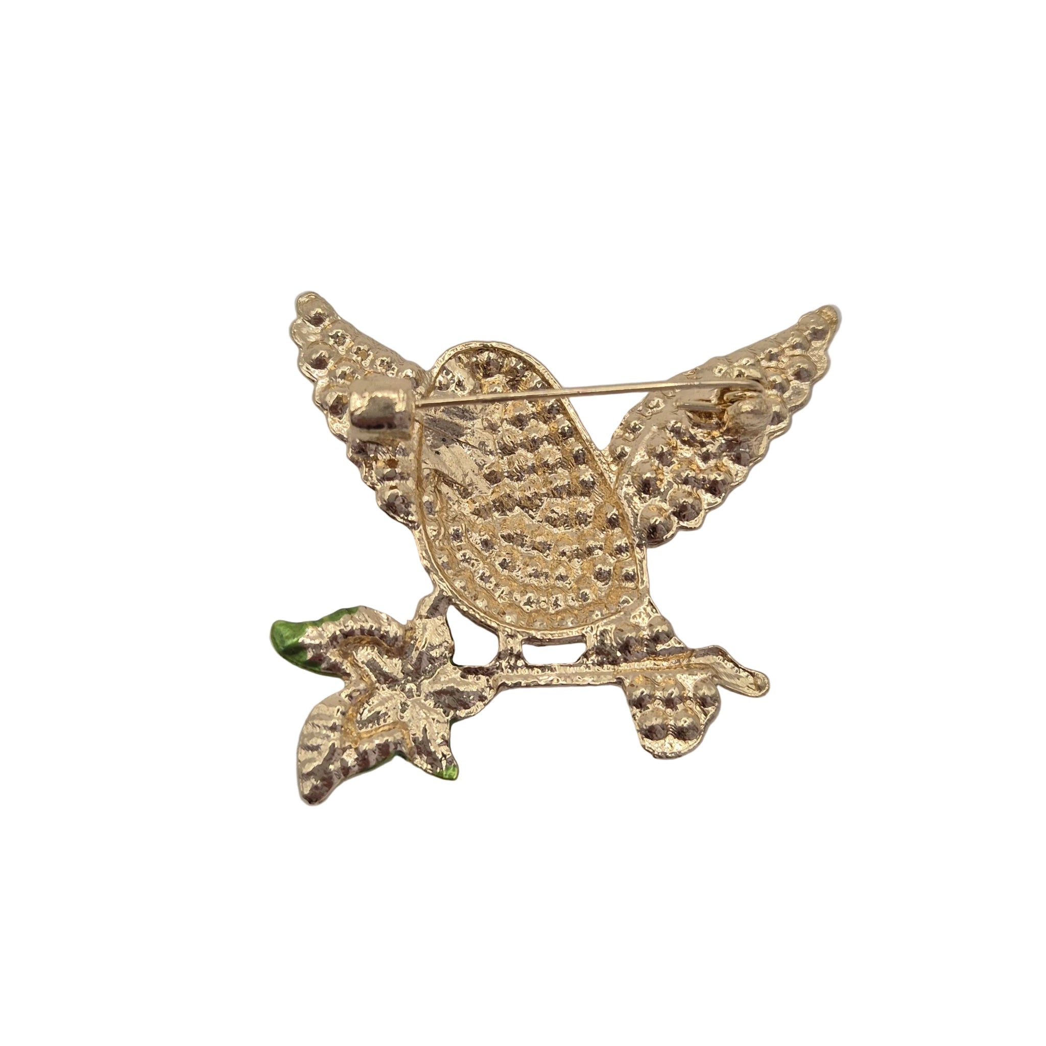 A gold-tone bird brooch with textured wings and a small green accent on the branch, photographed on a plain white background.