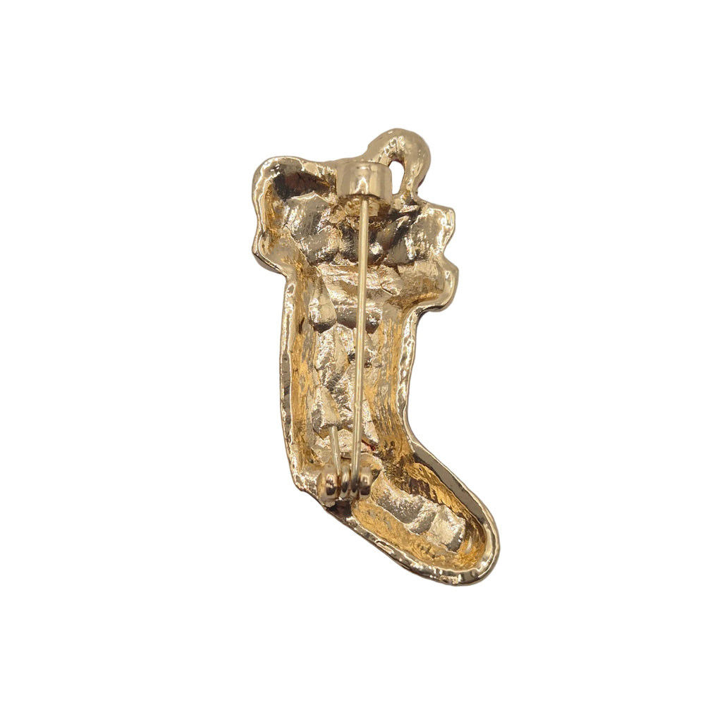 A gold-colored textured boot-shaped brooch with a visible pin mechanism on the back, photographed on plain white background.