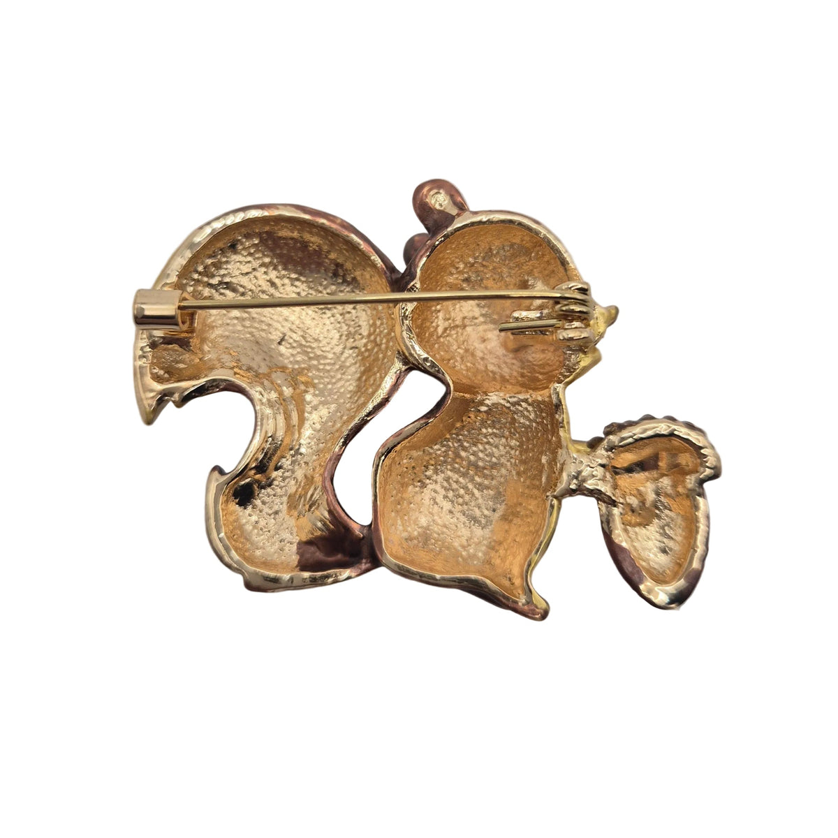 Reverse gold tone side of a squirrel holding an acorn brooch showing pin mechanism, displayed against a plain white background.