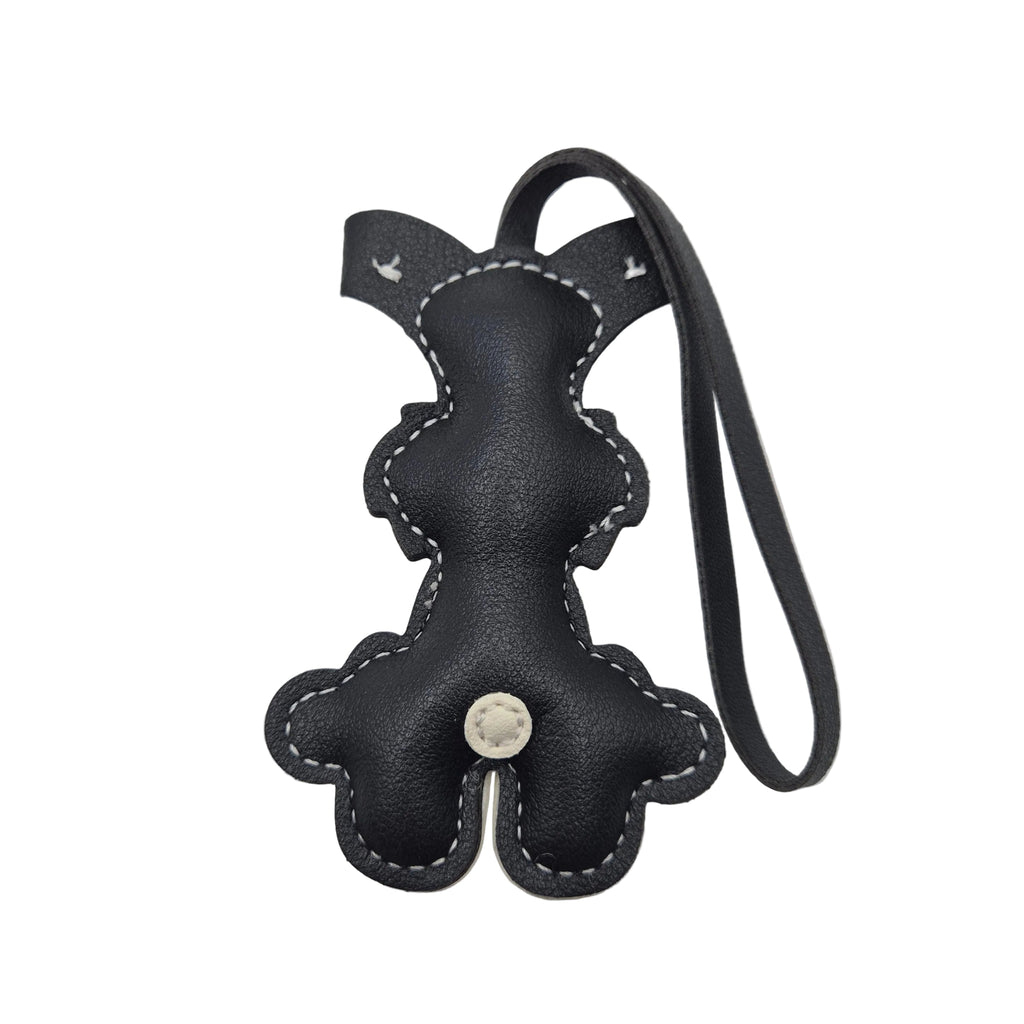 A small dog-shaped leather keychain or bag charm with a black and cream colour scheme, featuring a loop strap at the top, photographed on a white background showing the reverse side.