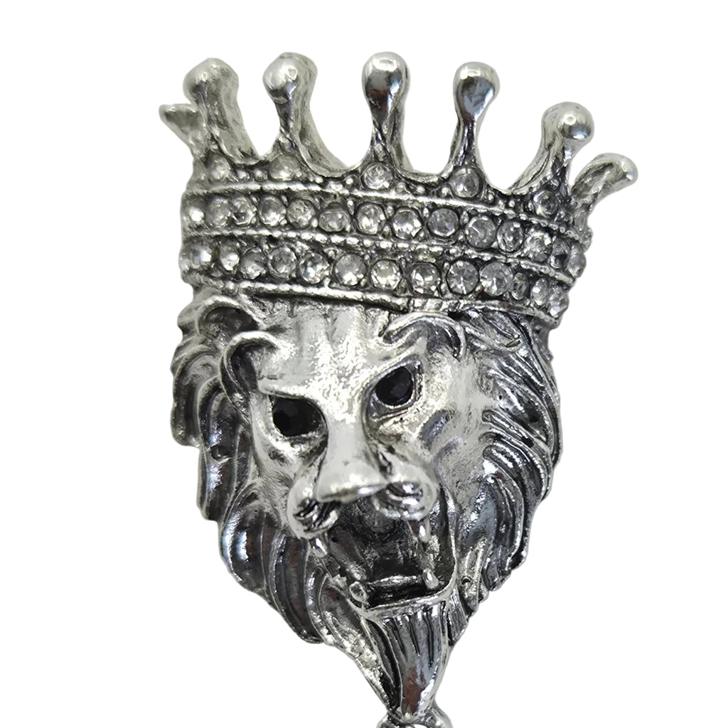 Silver-tone lion head brooch with a crown and dangling chains, shown on a  white background, displaying rhinestone detailing.