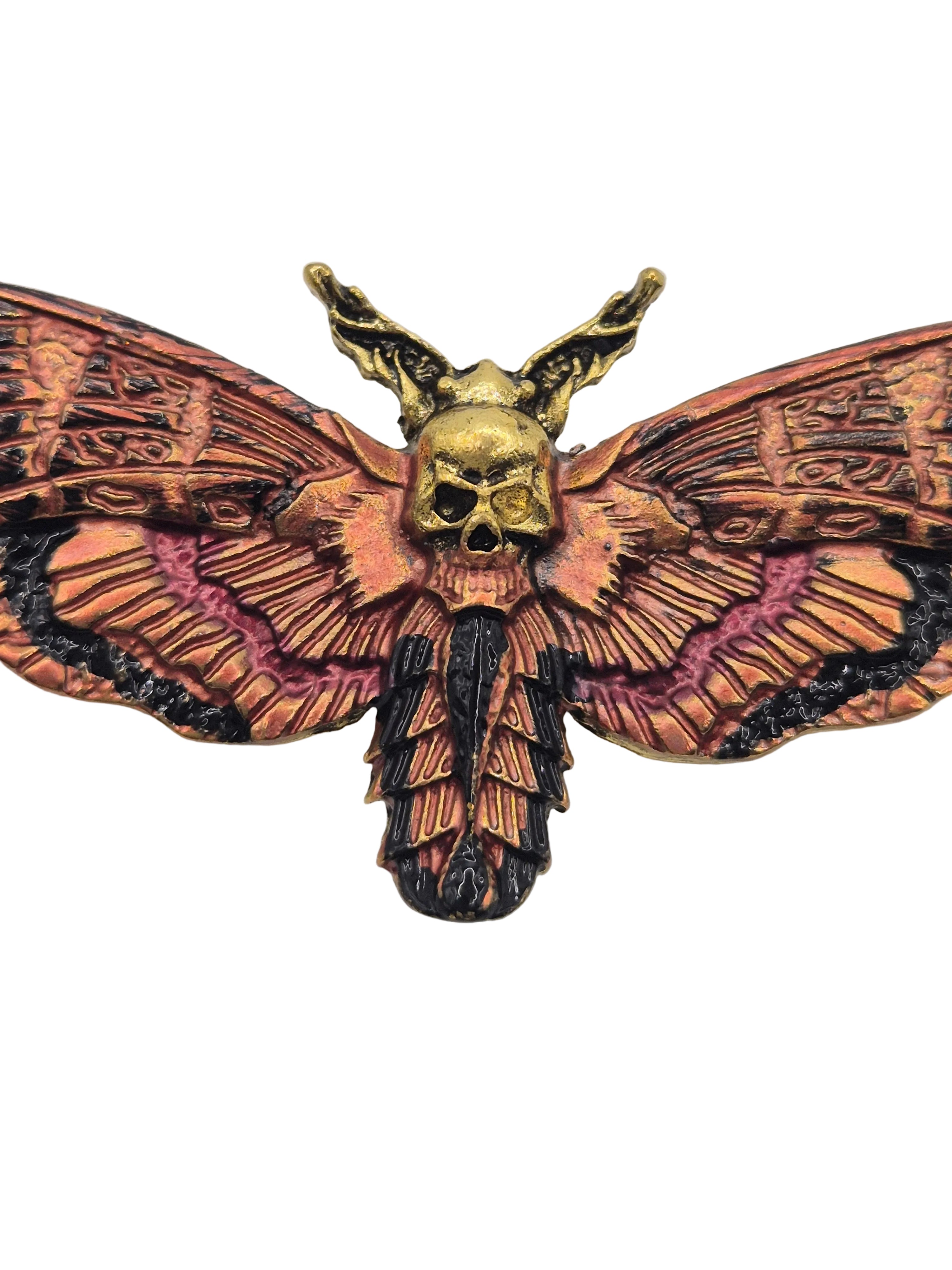 Decorative moth brooch with intricate patterns on a plain background