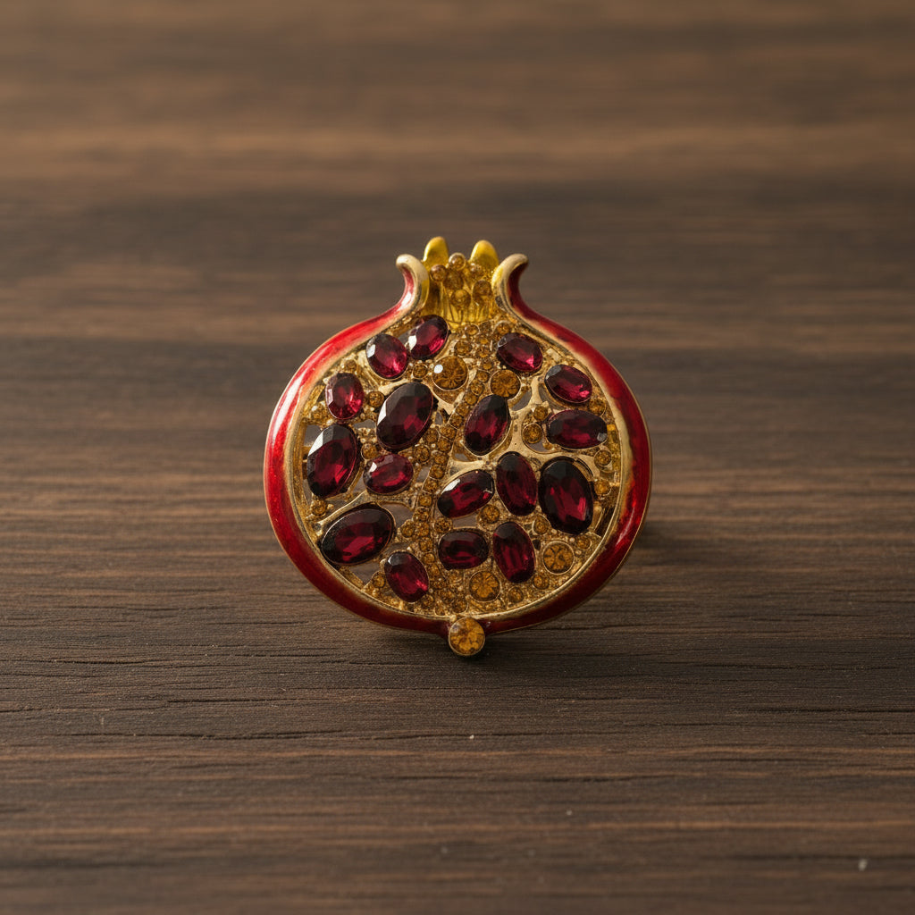  pomegranate brooch with red gemstones and gold accents on a white background