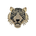 A gold and black tiger head brooch embellished with clear rhinestones, shown against a plain white background.