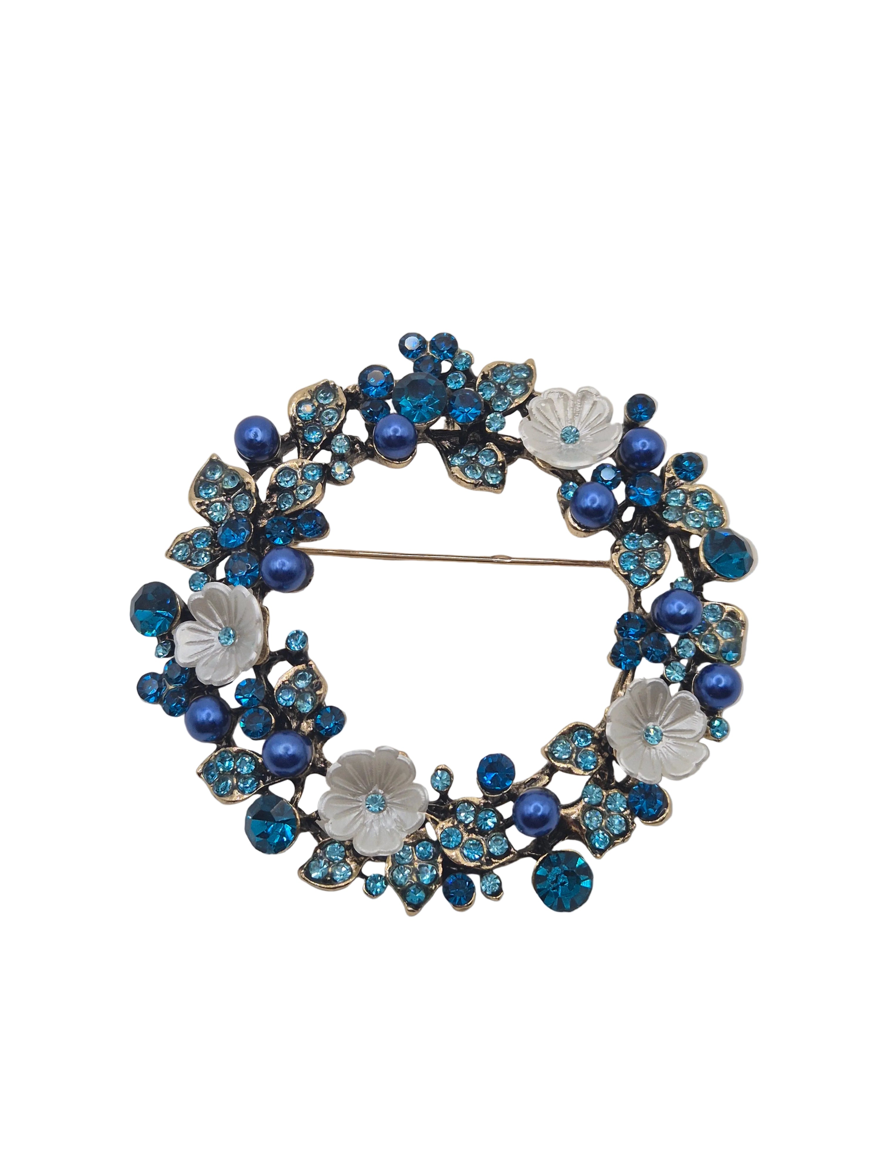 Decorative brooch with blue and silver floral design on a white background