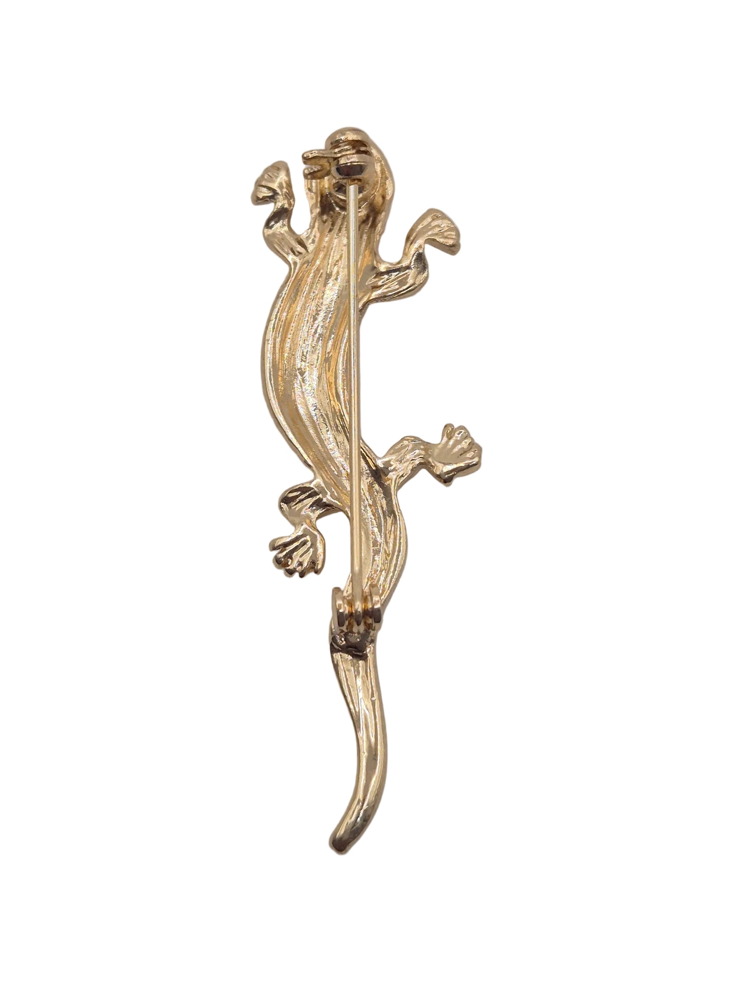 A gold-toned lizard-shaped brooch with a textured, organic finish, shown against a plain white background.