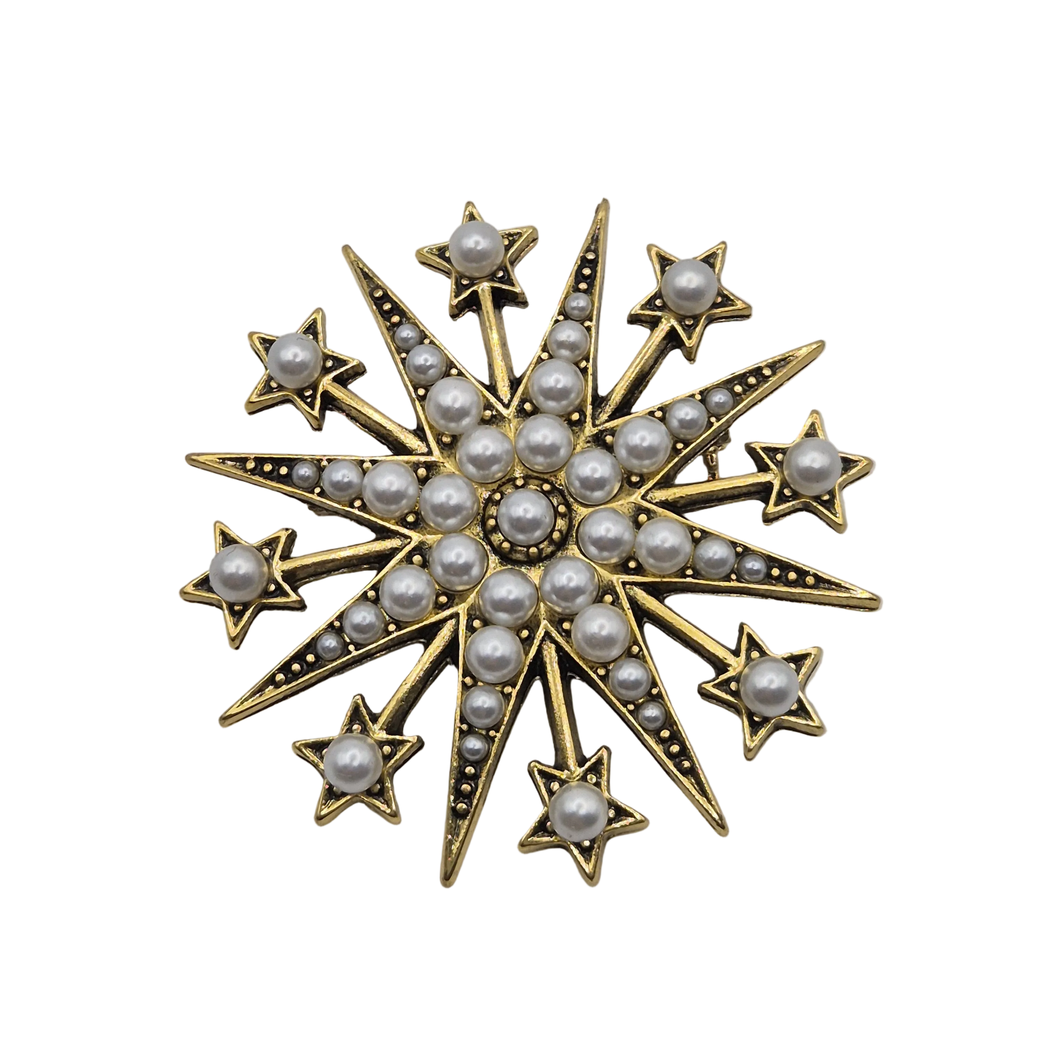 A gold starburst brooch decorated with white pearls and small black-set accents, isolated on a white background.