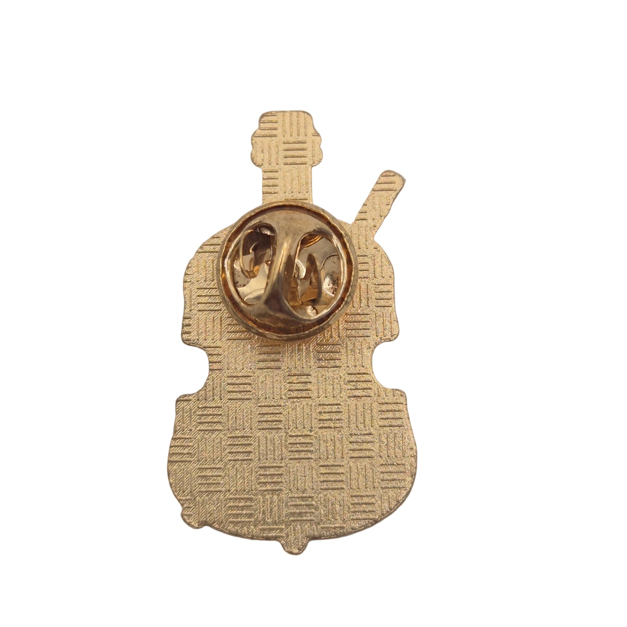 A gold-coloured metal pin shaped like a violin, showing the back side with a woven texture pattern and a gold-tone spring ring clasp, set against a plain white background.
