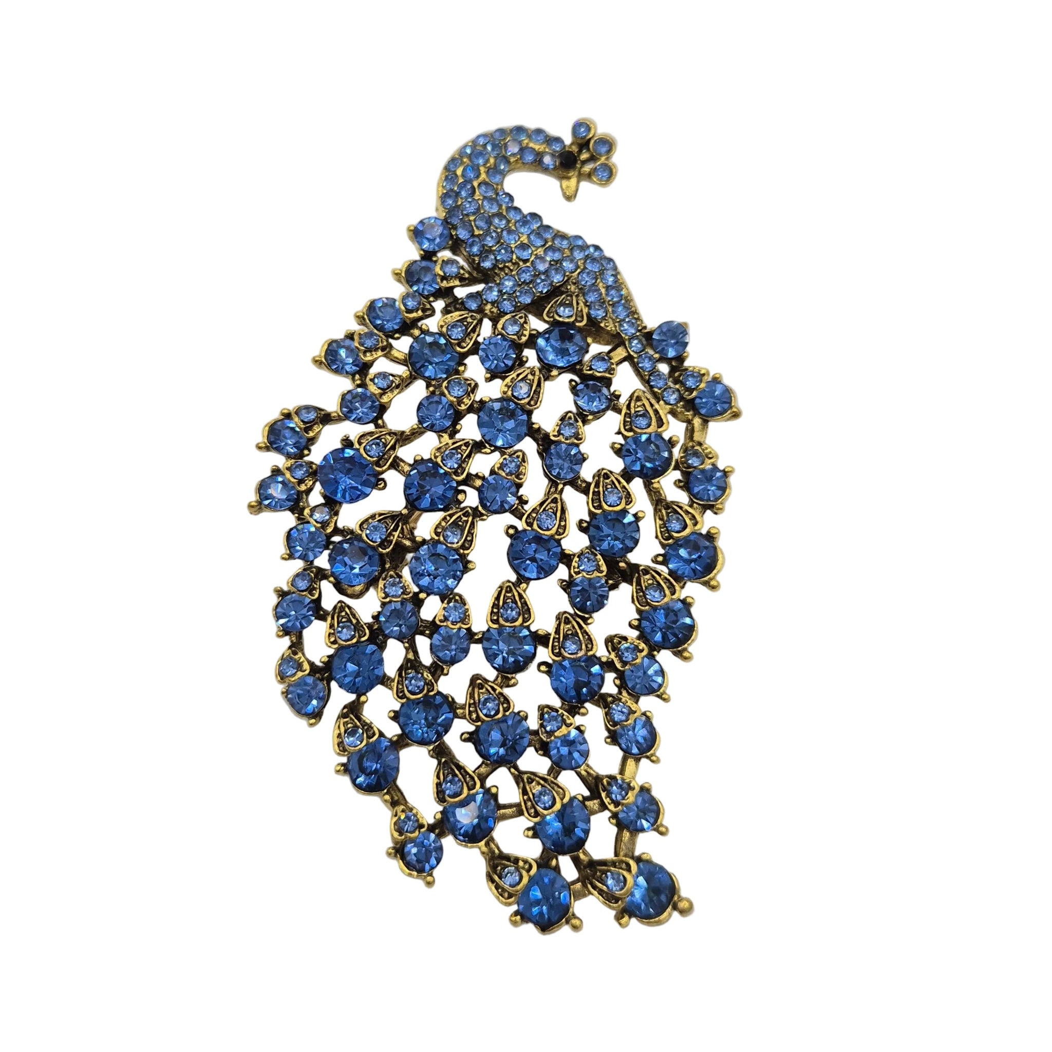 A peacock-shaped brooch featuring blue rhinestones set in gold-tone metal, displayed on a plain white background.