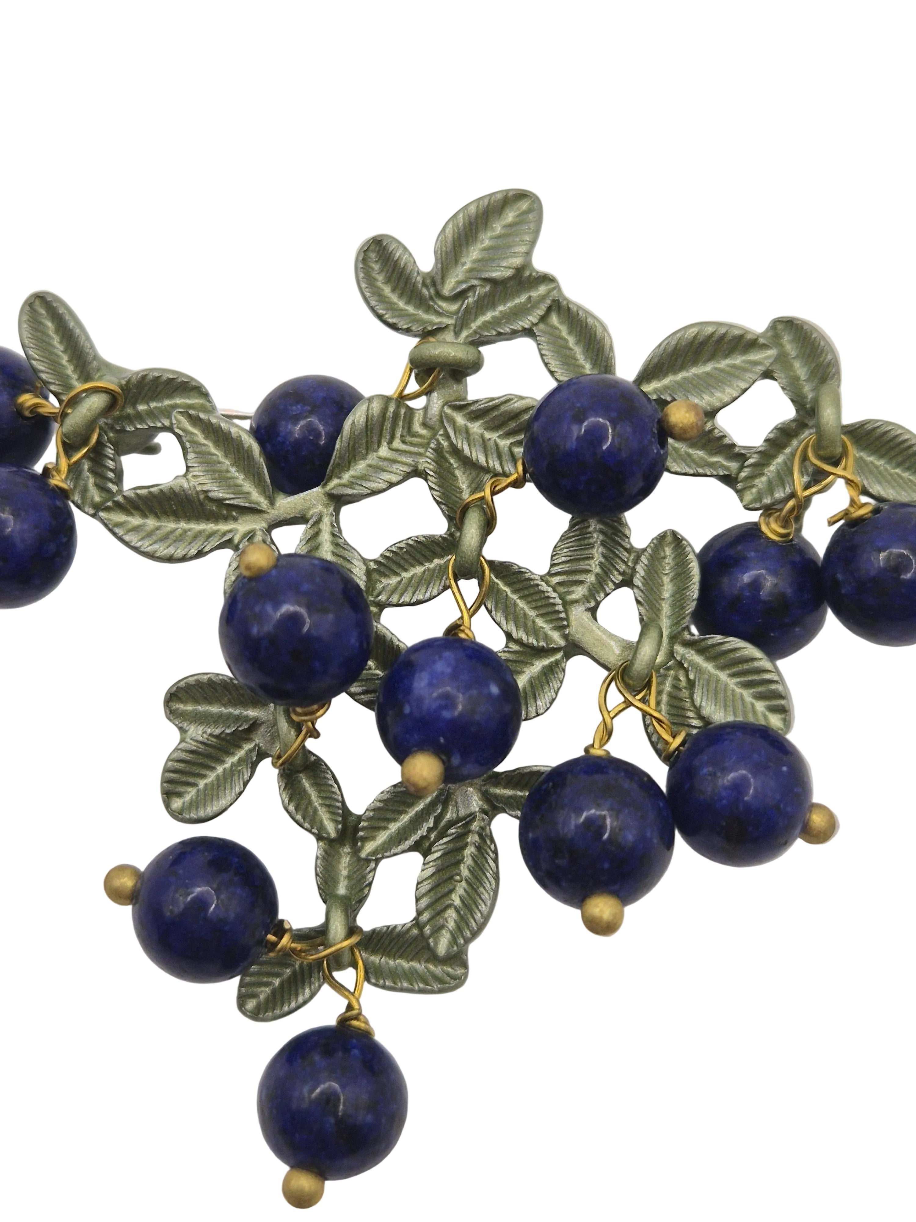 blueberry brooch with blue beads and green leafy patterns on a white background