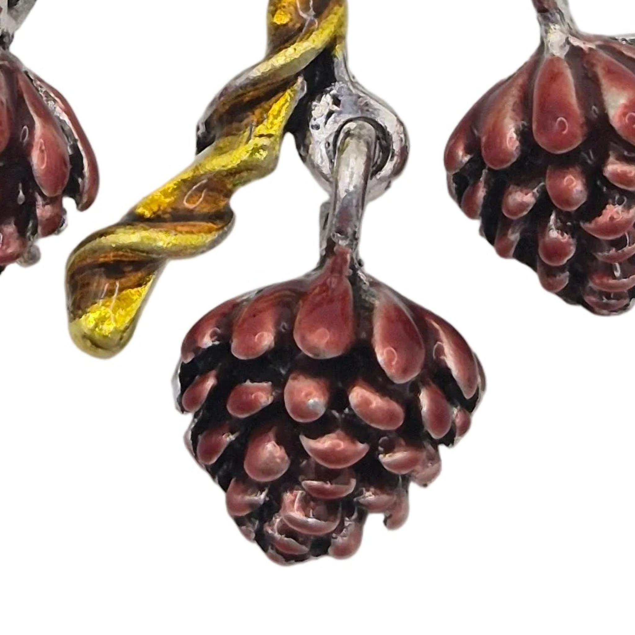 Close up of a textured pendant pinecone dangling from a brooch. Displayed against a plain white background.