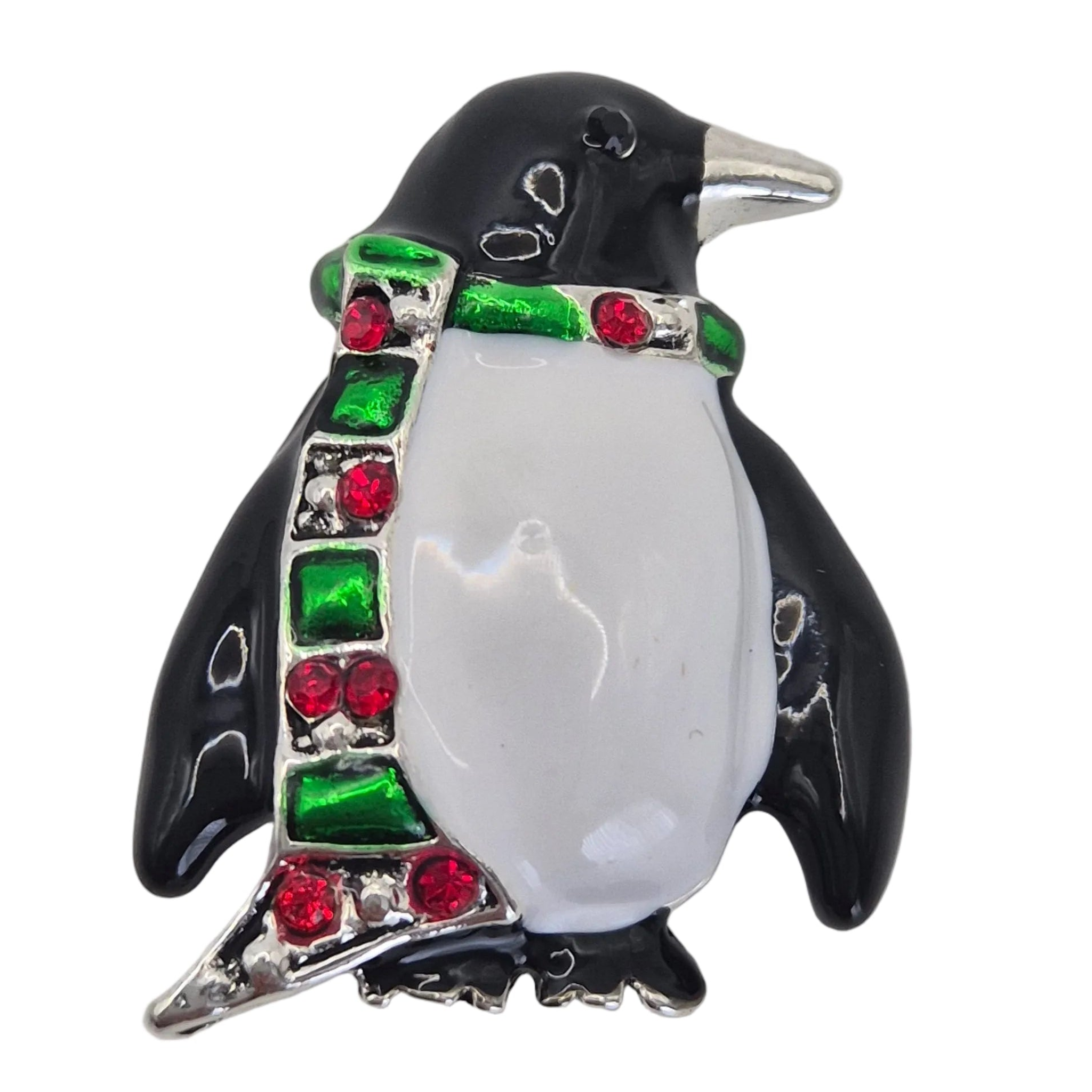 A penguin-shaped brooch with a glossy black and white enamel body, decorated with a green and red patterned scarf outlined in silver-tone metal.