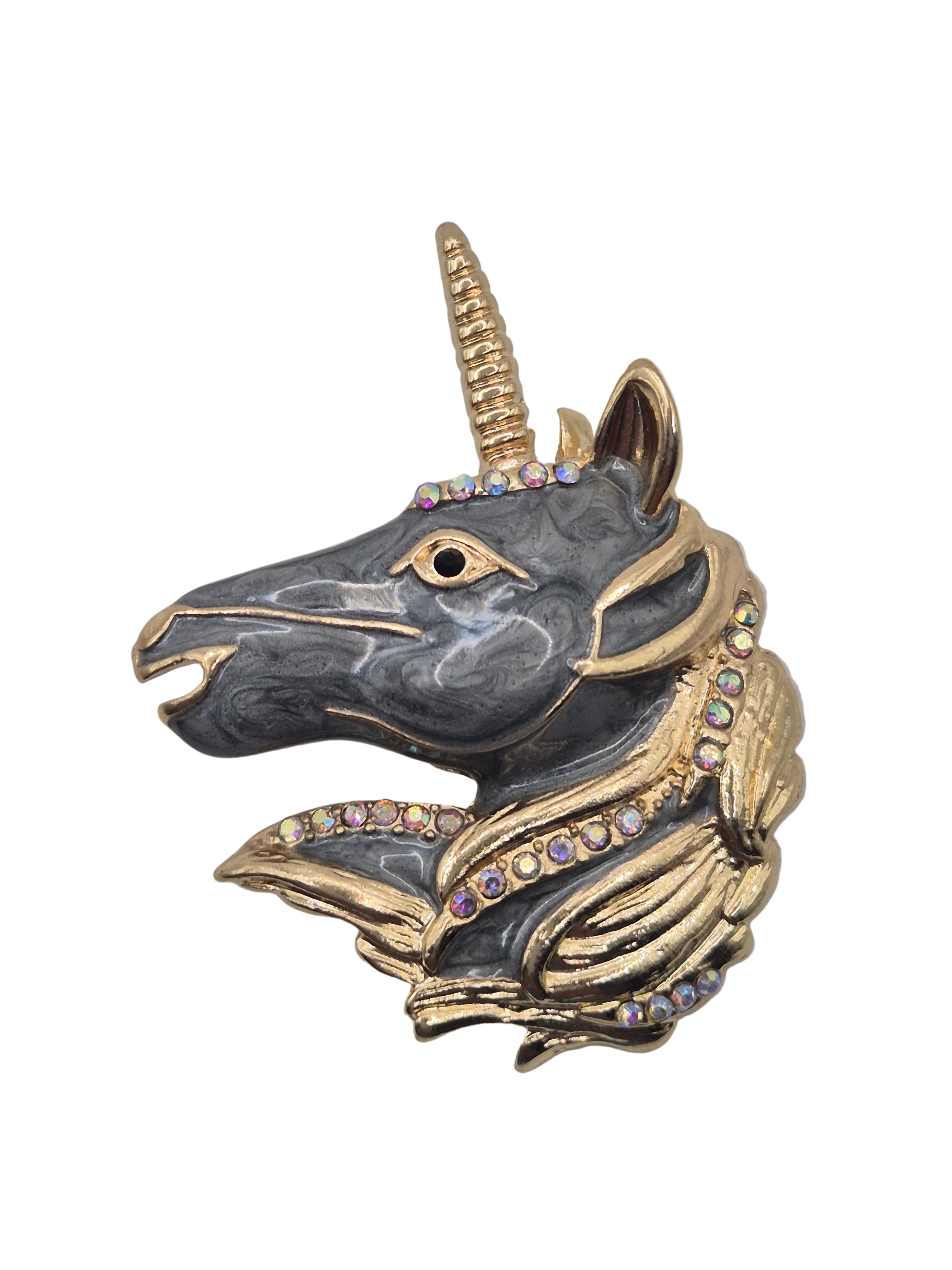Unicorn head brooch with gold and black details on a white background