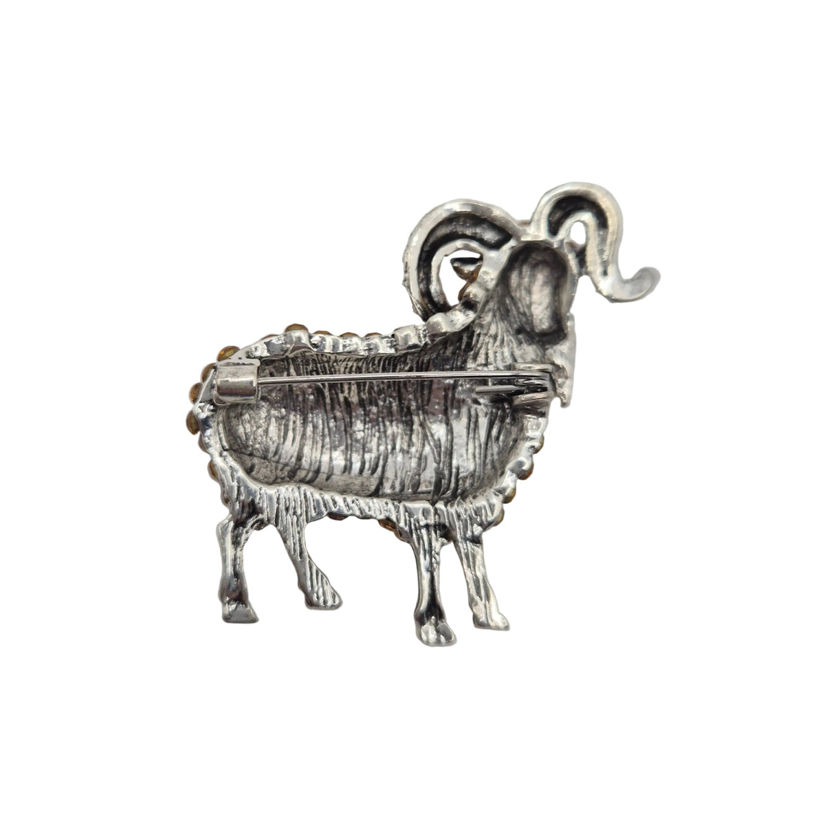 A small silver-toned ram or goat-shaped brooch with textured detailing and a curved horn, photographed on a plain white background.