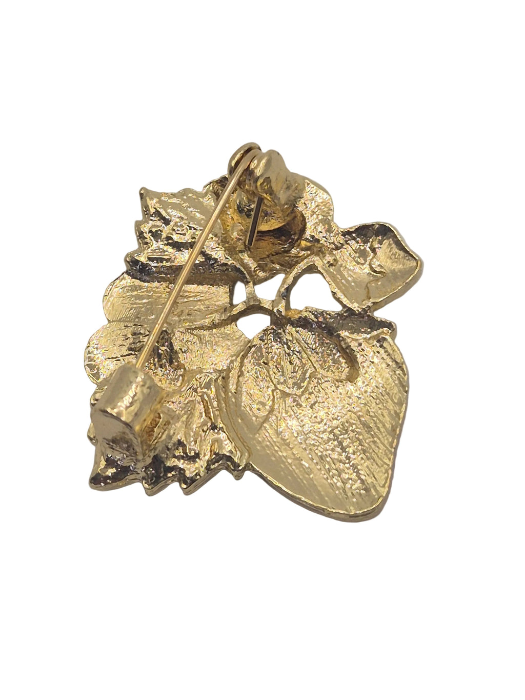 Reverse gold side of strawberry brooch on a plain white background. 