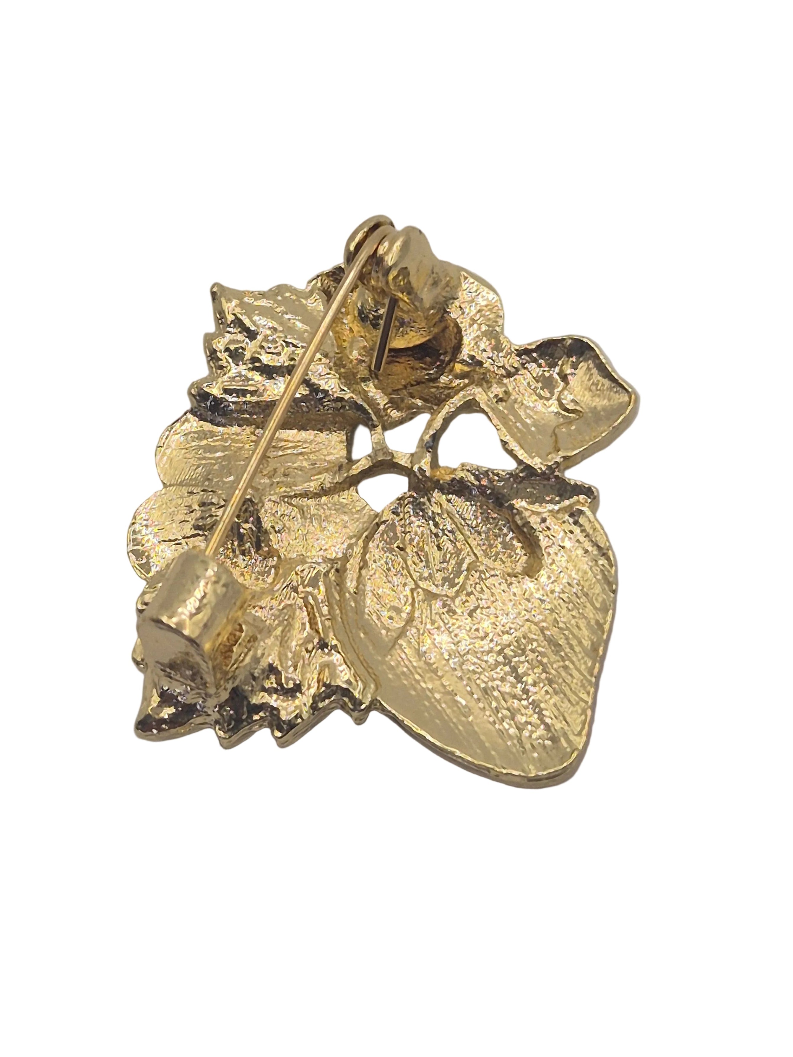 Reverse gold side of strawberry brooch on a plain white background. 