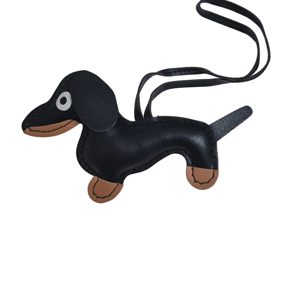 A black faux-leather dachshund-shaped keychain or bag charm with tan accents on the muzzle, paws, and inner ears, plus a black strap, photographed on a plain white background.