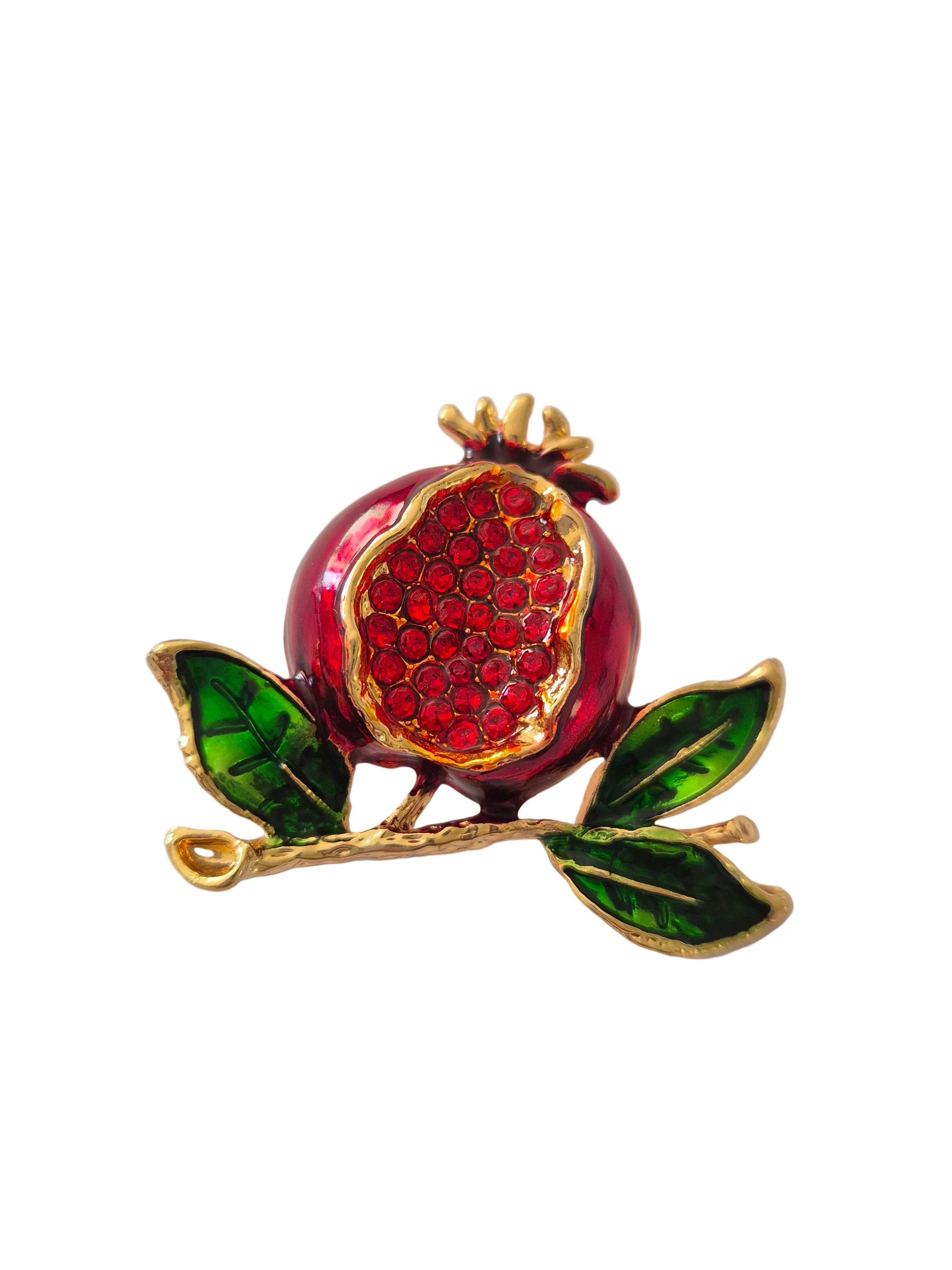 Brooch with a red pomegranate and green leaves on a white background