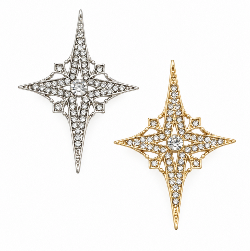 Two ornate star-shaped brooch pins on a plain white background, one in silver-tone metal and one in yellow-gold metal, both set with small clear stones.
