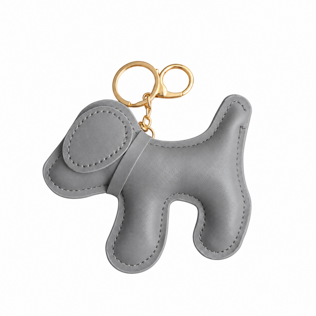 A light gray faux leather dog-shaped keychain bag charm with gold-tone metal key rings, shown on a plain white background.