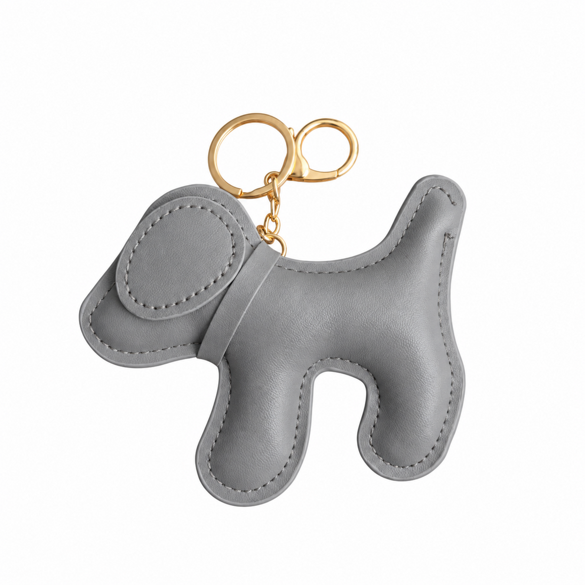 A light gray faux leather dog-shaped keychain bag charm with gold-tone metal key rings, shown on a plain white background.
