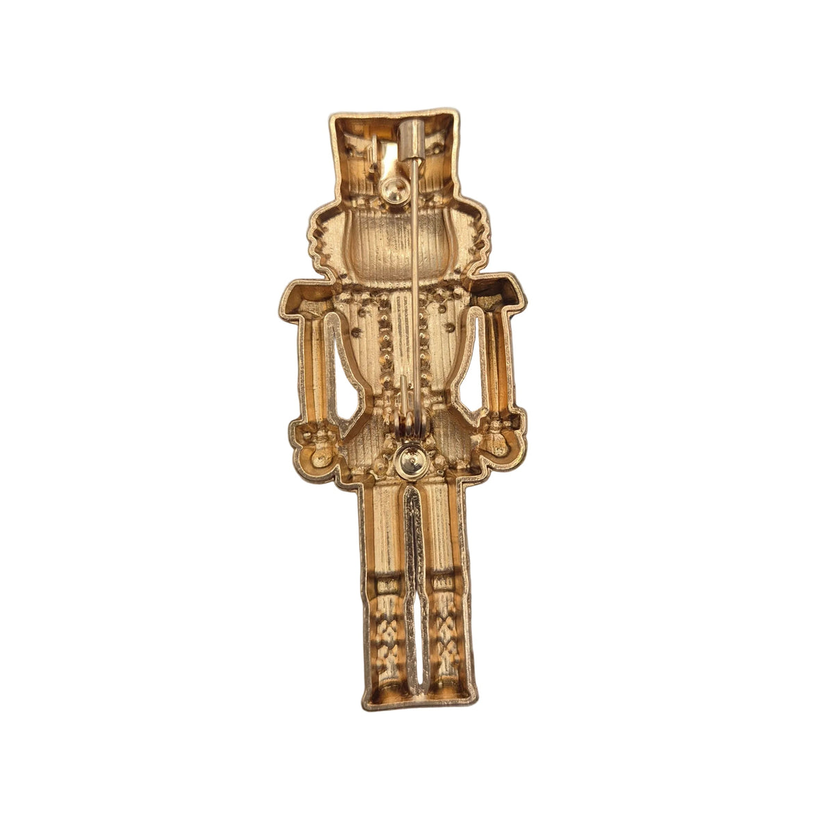 A small gold-toned brooch shaped like a nutcracker soldier, photographed against a plain white background.