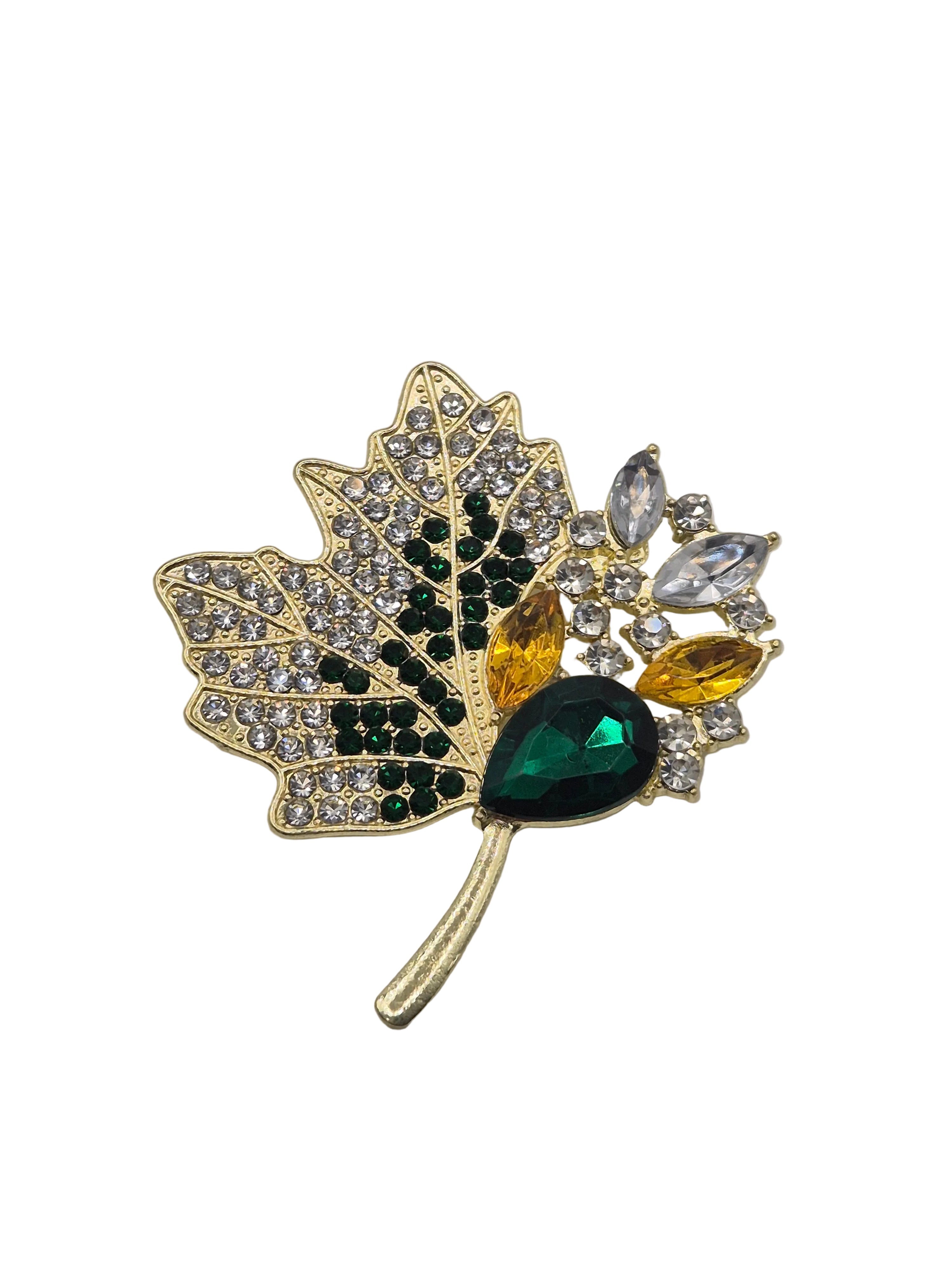 A gold-toned leaf-shaped brooch decorated with clear rhinestones, dark green stones, yellow marquise stones, and a large faceted green teardrop stone, shown on a plain white background.