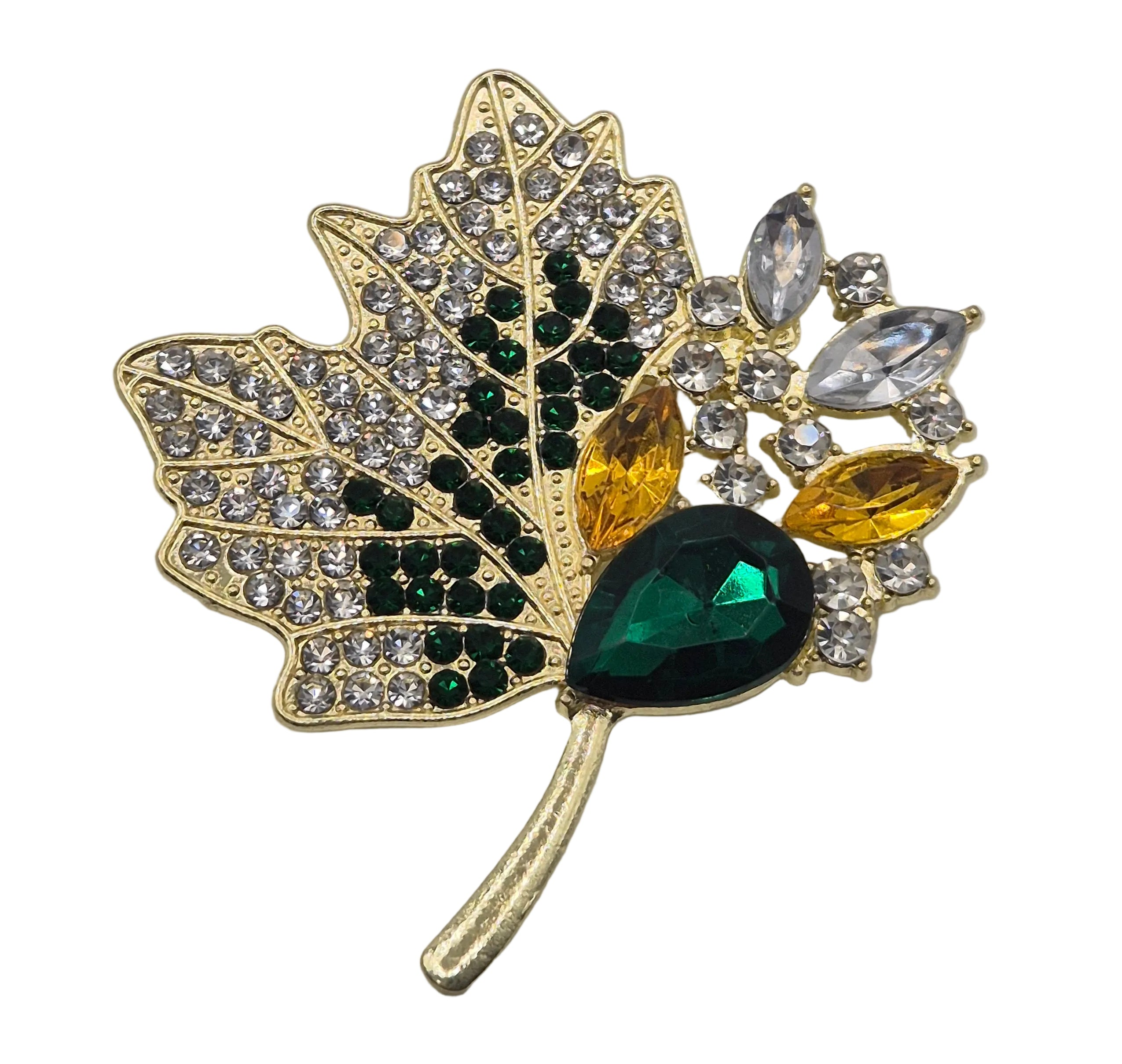 A gold-toned maple leaf brooch embellished with clear rhinestones, dark green stones, and yellow gemstones on a white background.