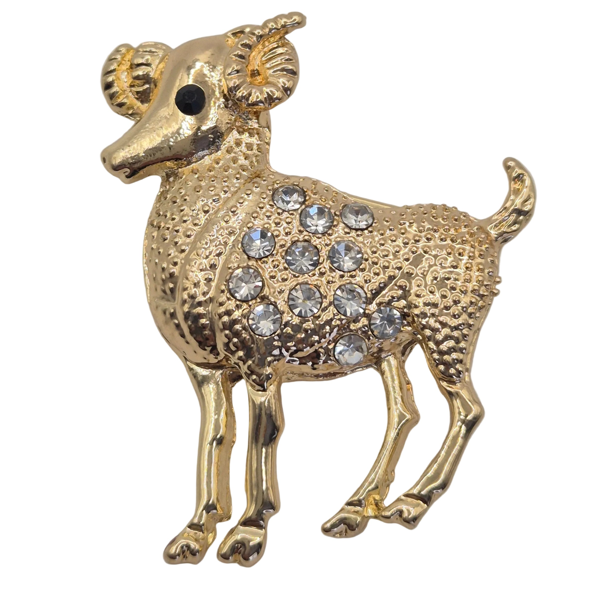 A gold-colored ram brooch decorated with clear rhinestones on its body, set against a plain white background. Close up view. 