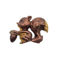 A small metallic squirrel brooch holding an acorn, shown on a plain white background. The brooch has a coppery rose-gold tone with yellow-gold highlights and a dark brown acorn.