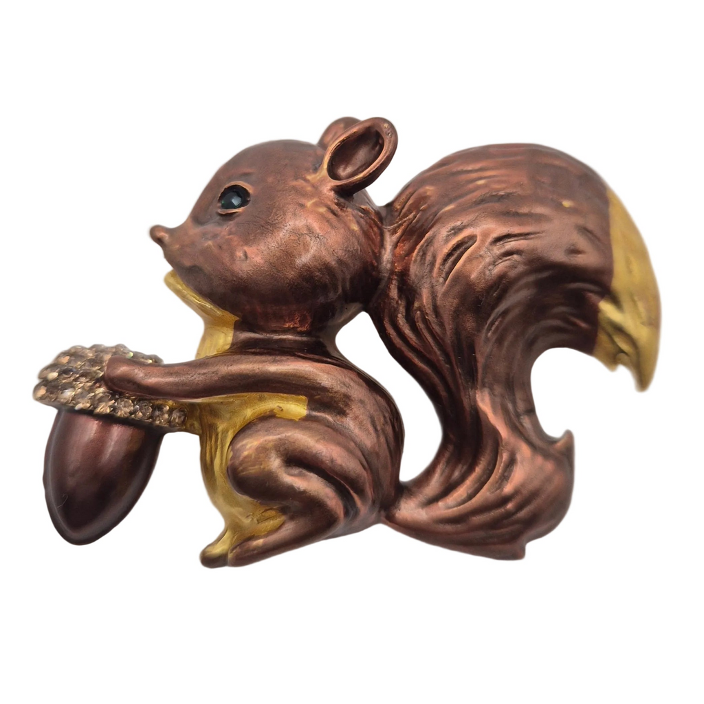 A metallic squirrel figurine holding an acorn, finished in a coppery bronze finish with gold accents on the tail tip, belly, and beak, set against a plain white background.