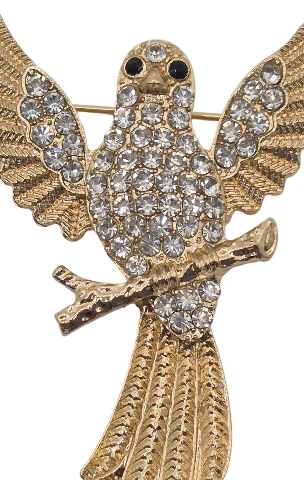 Gold-tone bird brooch embellished with clear rhinestones, featuring outstretched wings and a branch in its beak, shown on a plain white background.