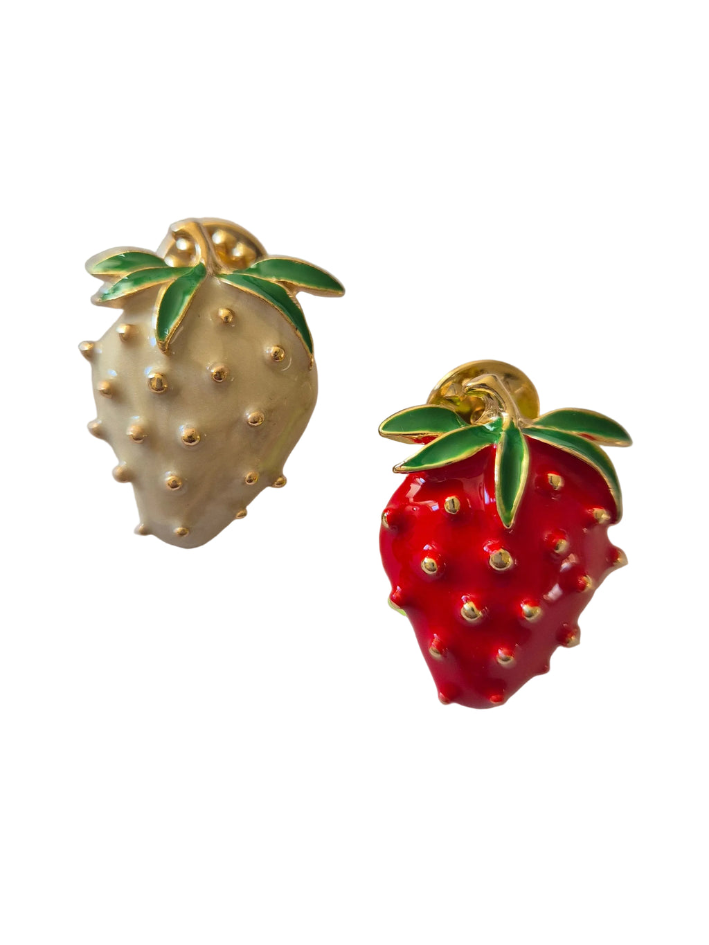 Two strawberry-shaped brooches, one gold and one red, on a white background.