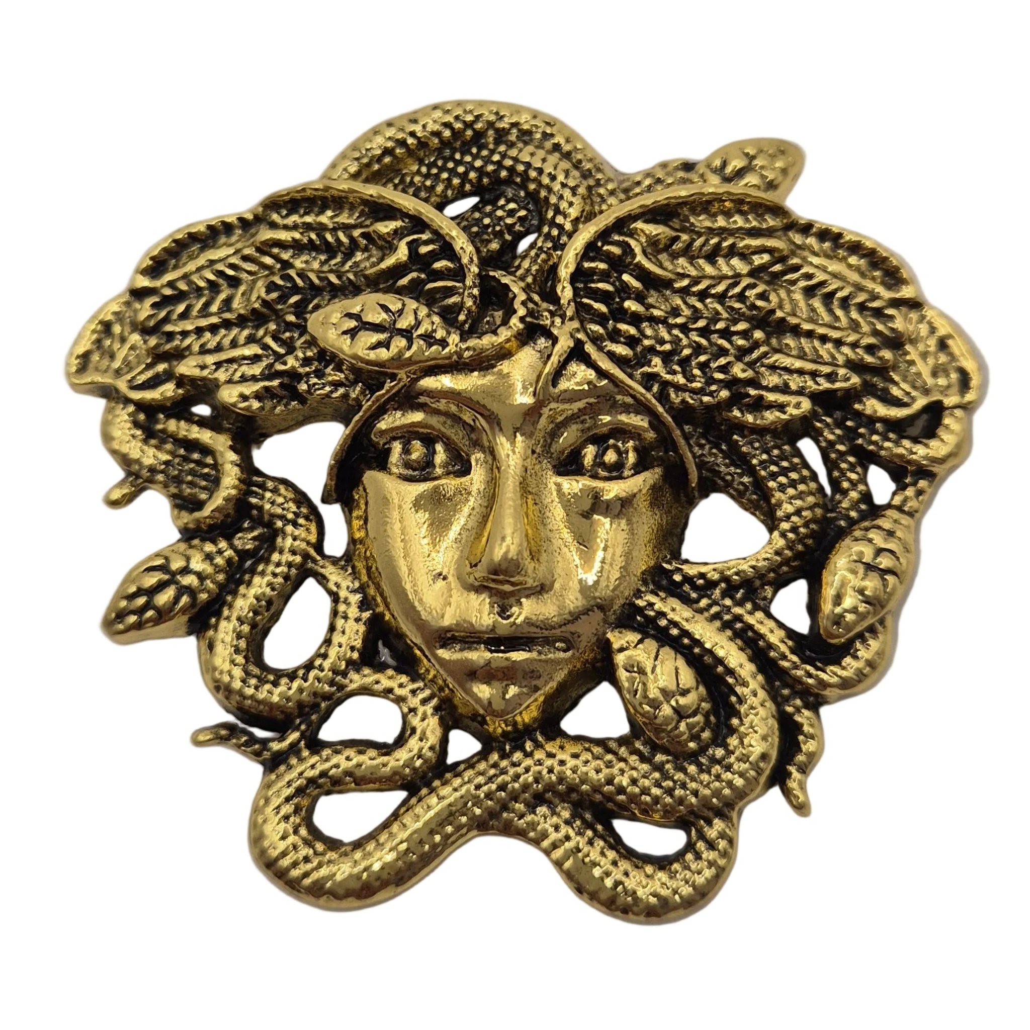 A gold-tone metal brooch featuring a Medusa head with snakes winding through her hair, shown on a plain white background.