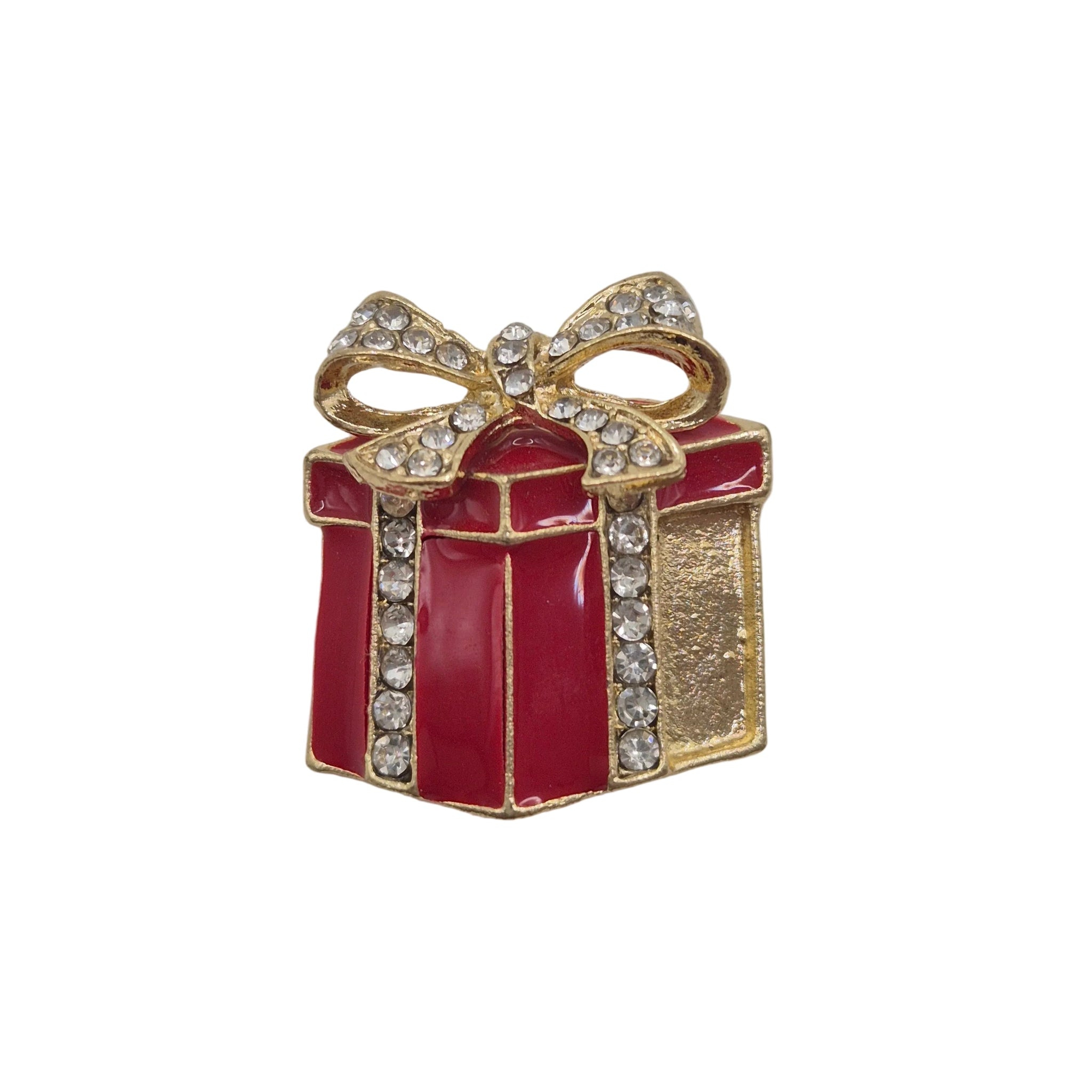 A small gift box brooch or charm with red enamel, gold-tone metal outlines, and clear rhinestones on the bow and edges, shown on a plain light background.