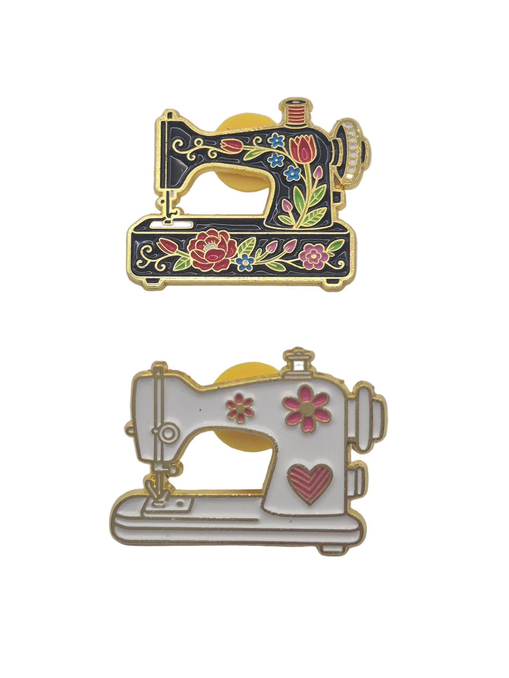Two decorative sewing machine enamel pins displayed side-by-side on a white background. The left pin features a black body with gold trim and colorful floral embroidery.