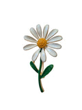 Daisy-shaped brooch with white petals, yellow center, and green stem on a white background