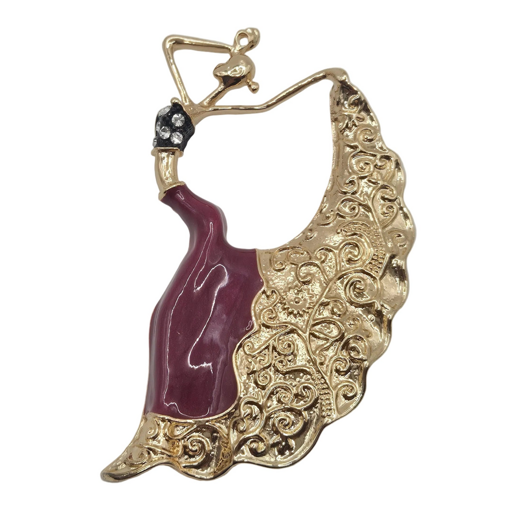 A gold-tone brooch shaped like a dancing woman with a large, ornate fan-like skirt. The dress portion is glossy deep burgundy, while the skirt features intricate scrollwork in gold-tone metal.