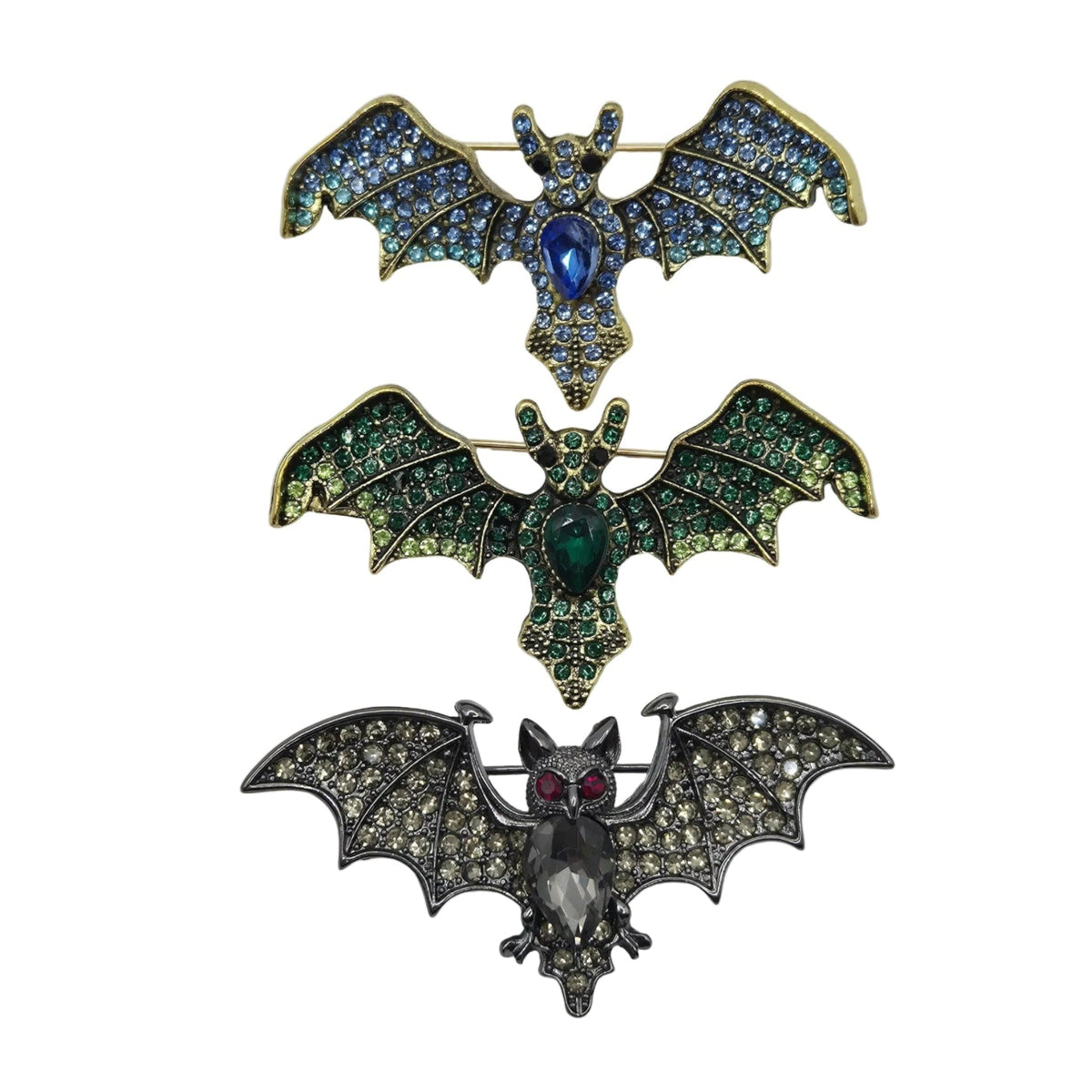 Three bat-shaped brooches arranged vertically on a plain white background. The top brooch has blue and green rhinestones with a blue center stone and gold-tone edges.