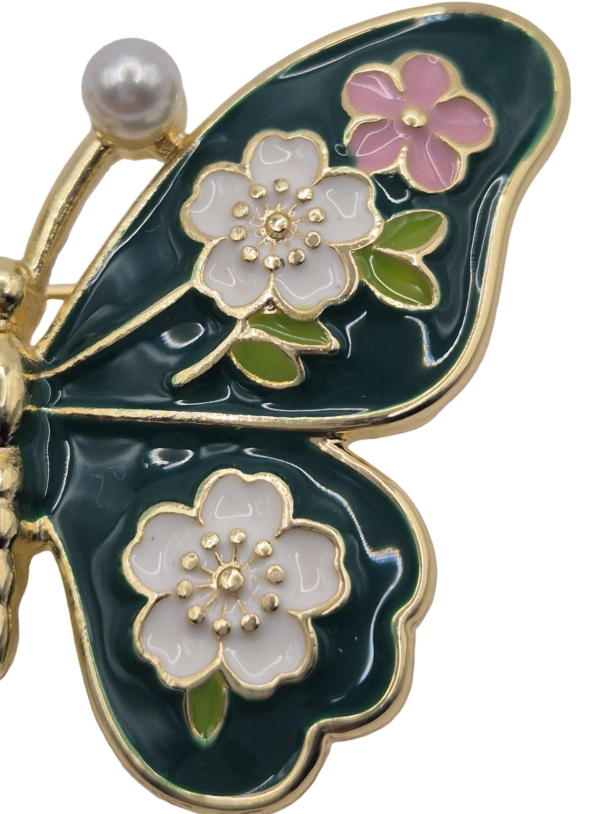 Butterfly brooch with floral designs and a pearl on a white background
