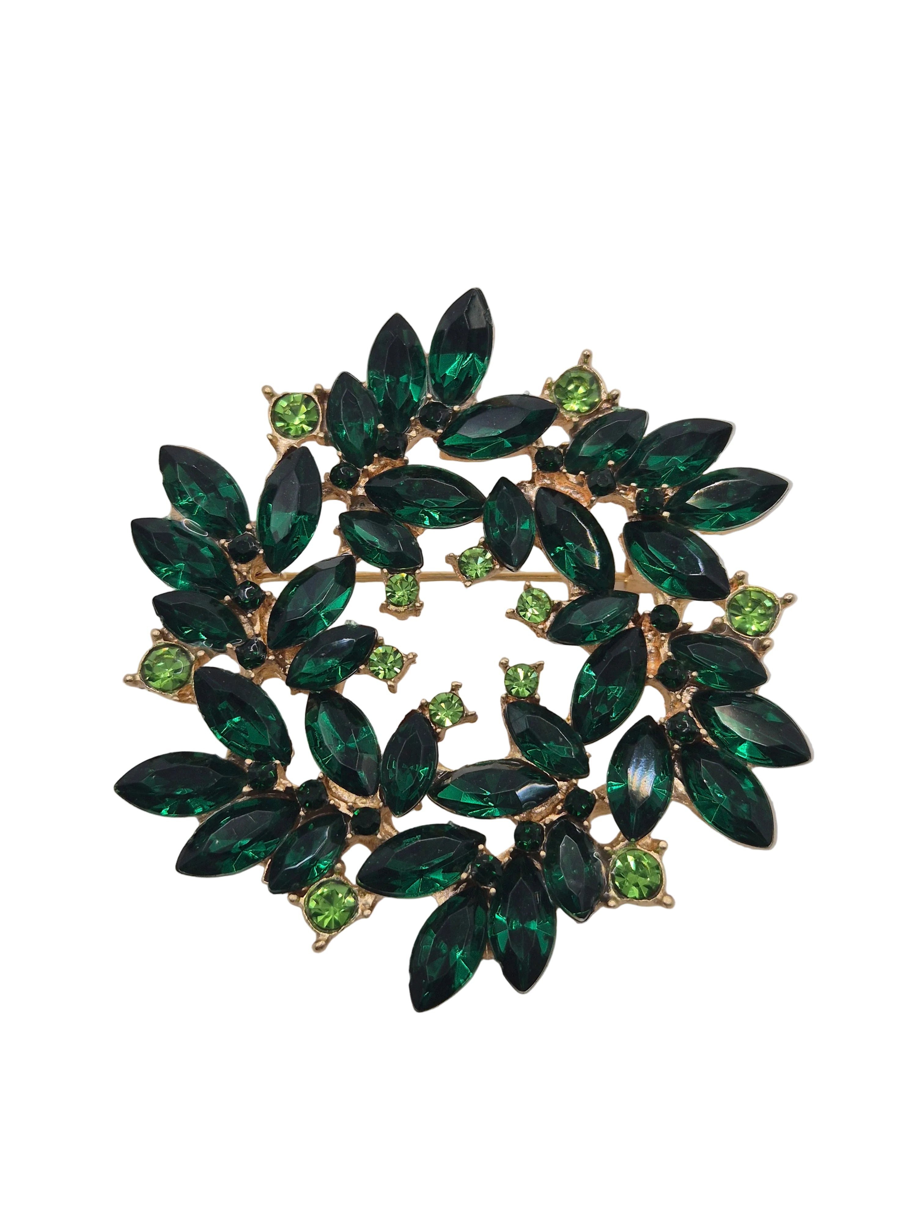 Green gemstone brooch with gold setting on a gray background