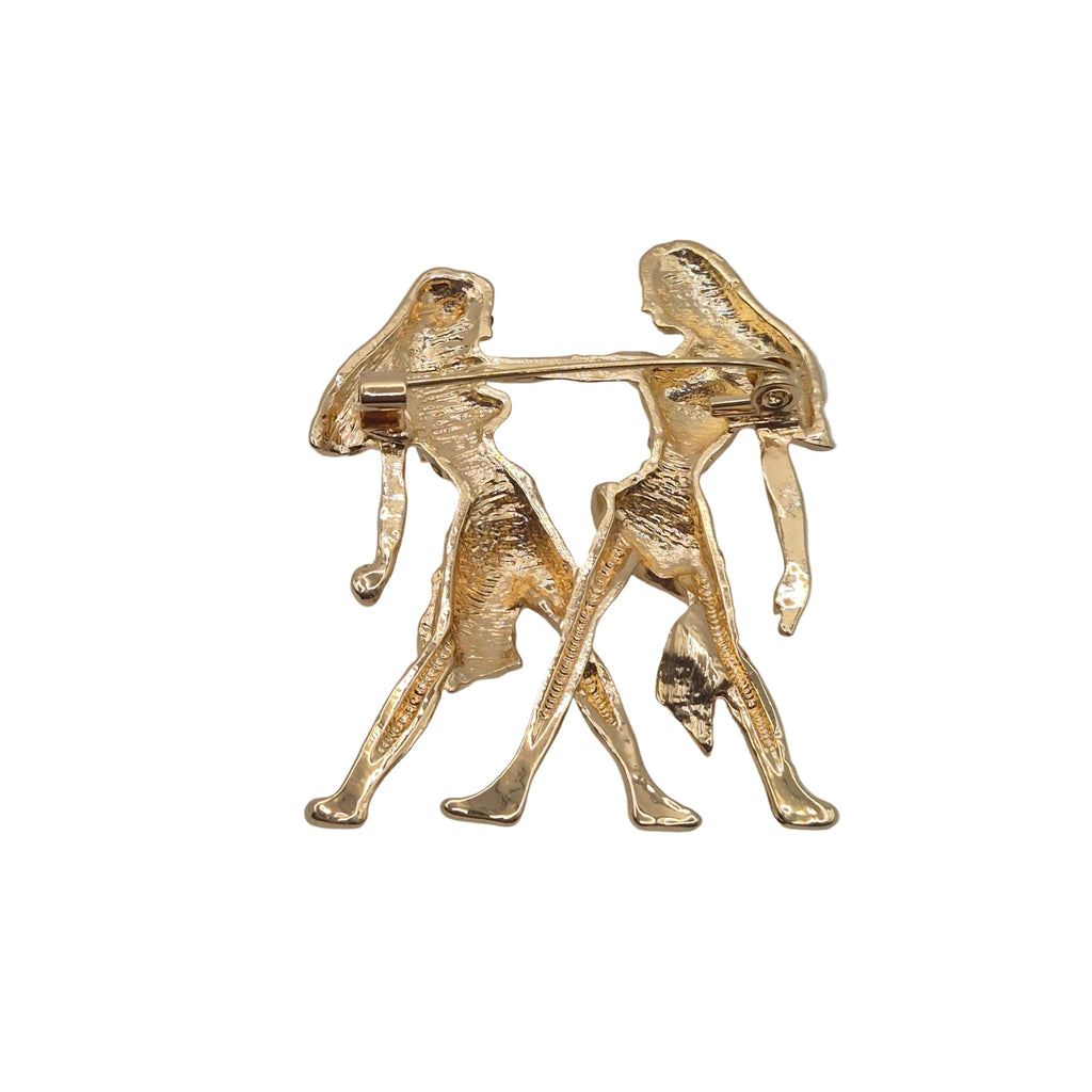 A gold tone Gemini zodiac sign brooch showing the reverse side with pin mechanism. Shown against a plain white background.