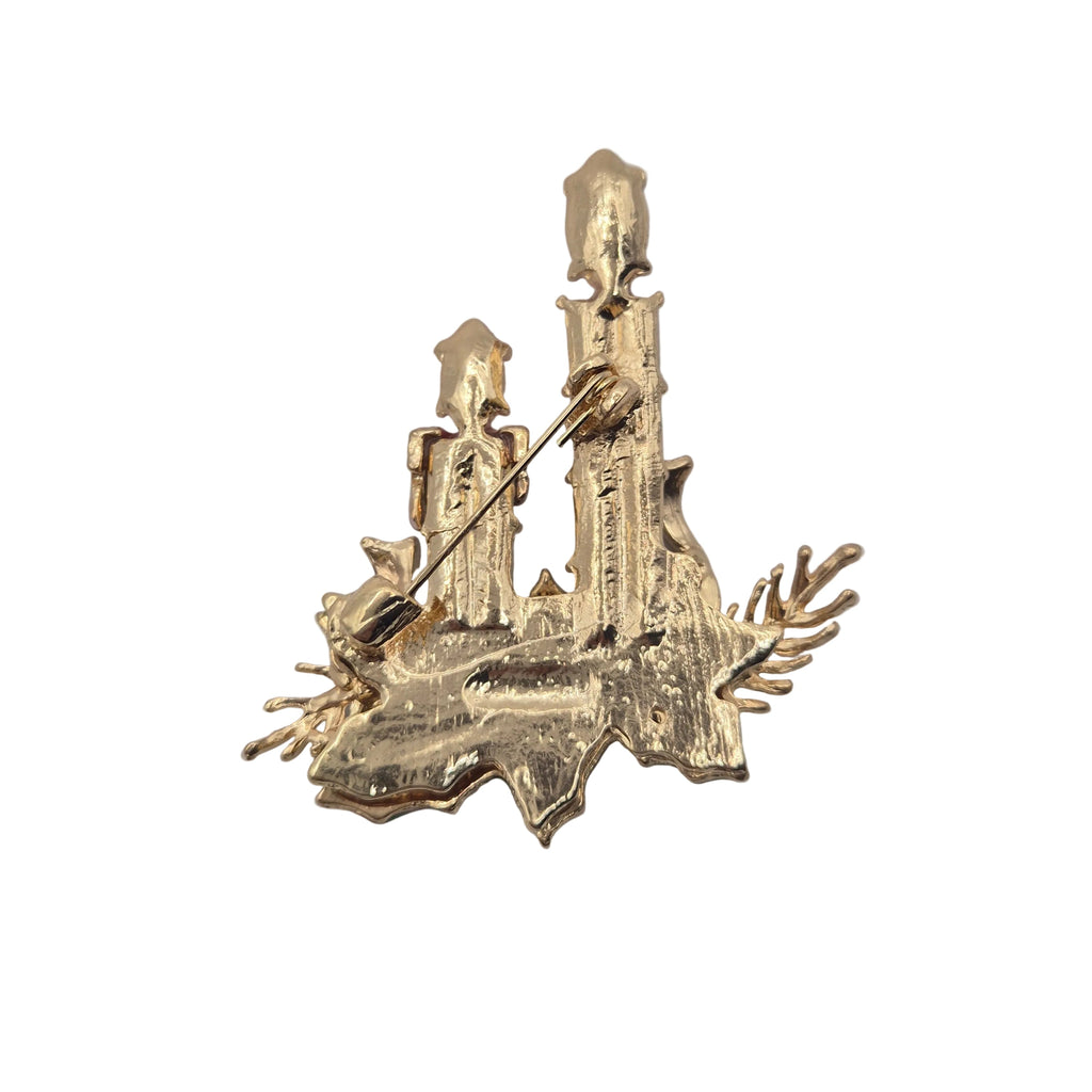 Reverse gold-tone side of a Christmas candle brooch featuring pin mechanism. Displayed against a plain white background.