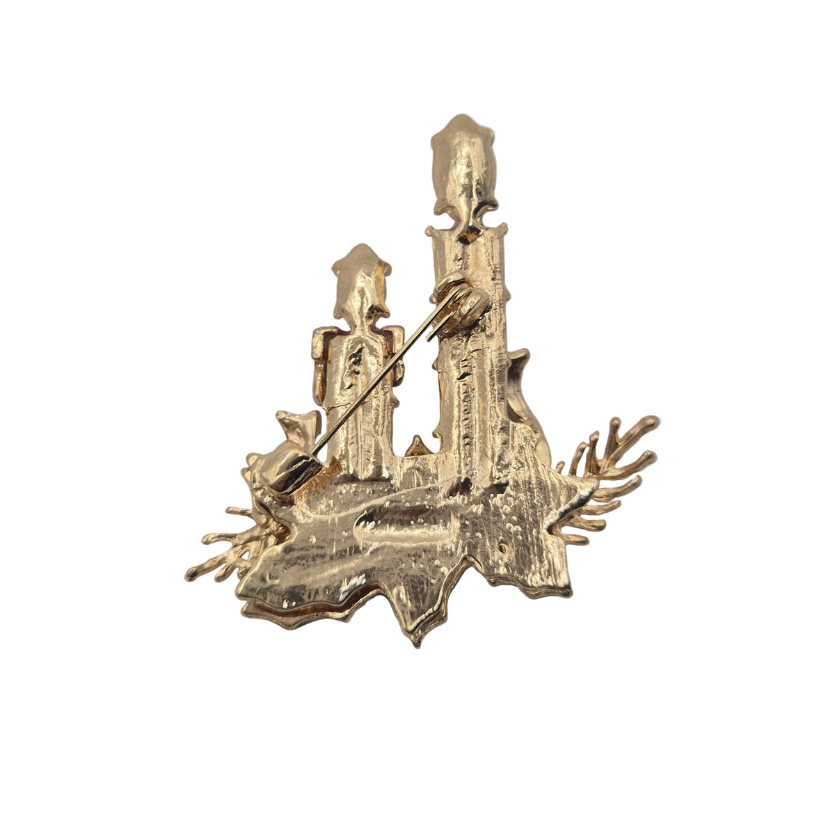 Reverse gold-tone side of a Christmas candle brooch featuring pin mechanism. Displayed against a plain white background.
