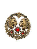 Decorative lion brooch with two animals and red gemstones on a light gray background